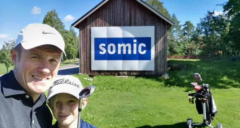 Mies ja lapsi tapahtumassa golfmailojen kanssa.